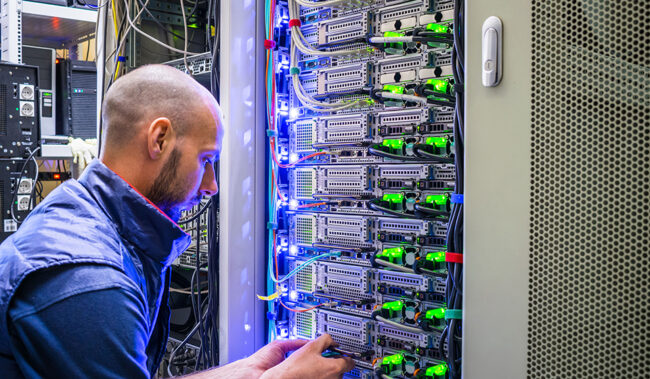 A man works with telecommunications. The technician switches the Internet cable of the powerful routers. A specialist connects the wires in the server room of the data center.